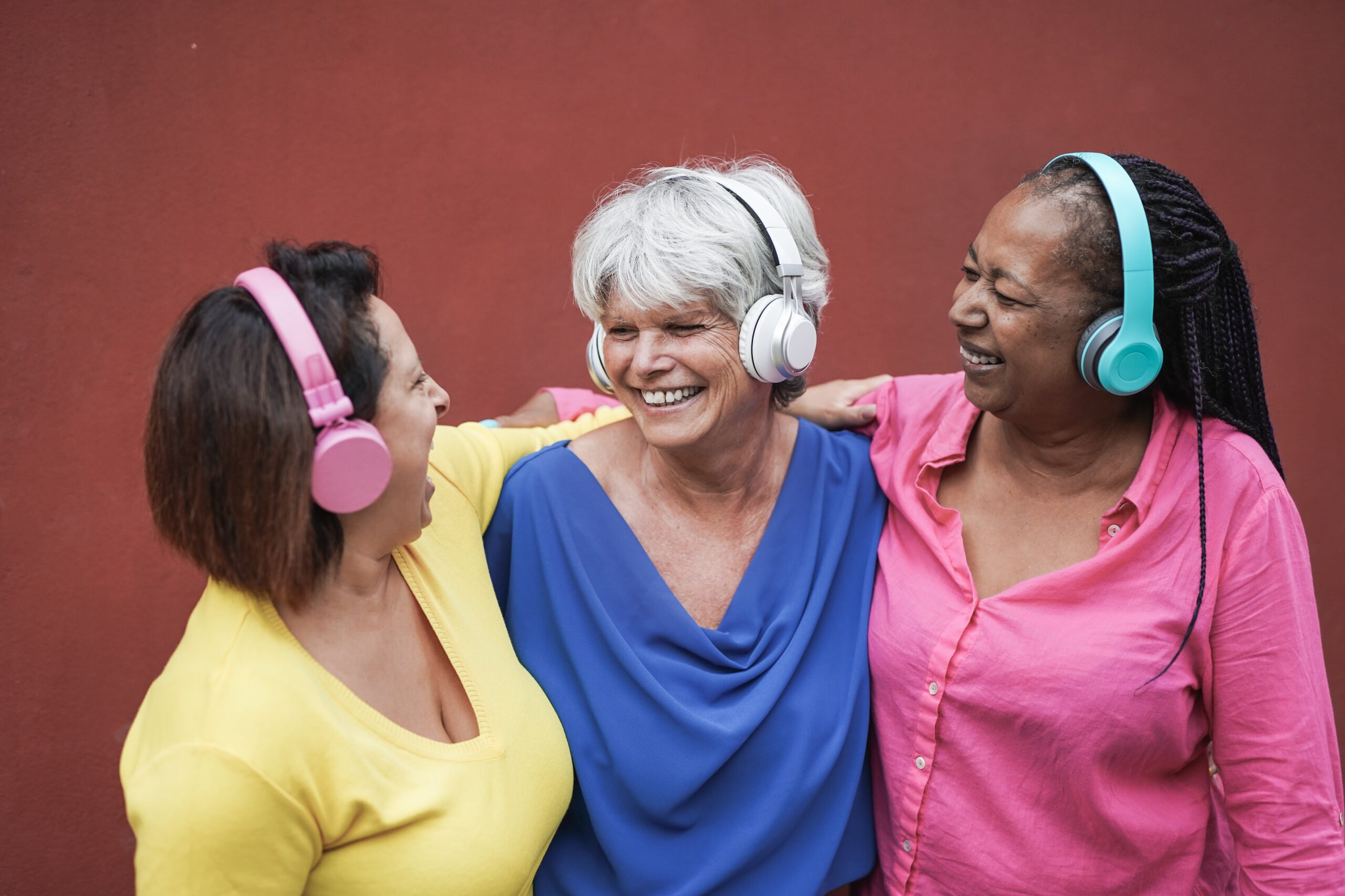 Elderly multiracial women having fun with technology while listening music with wireless headphone