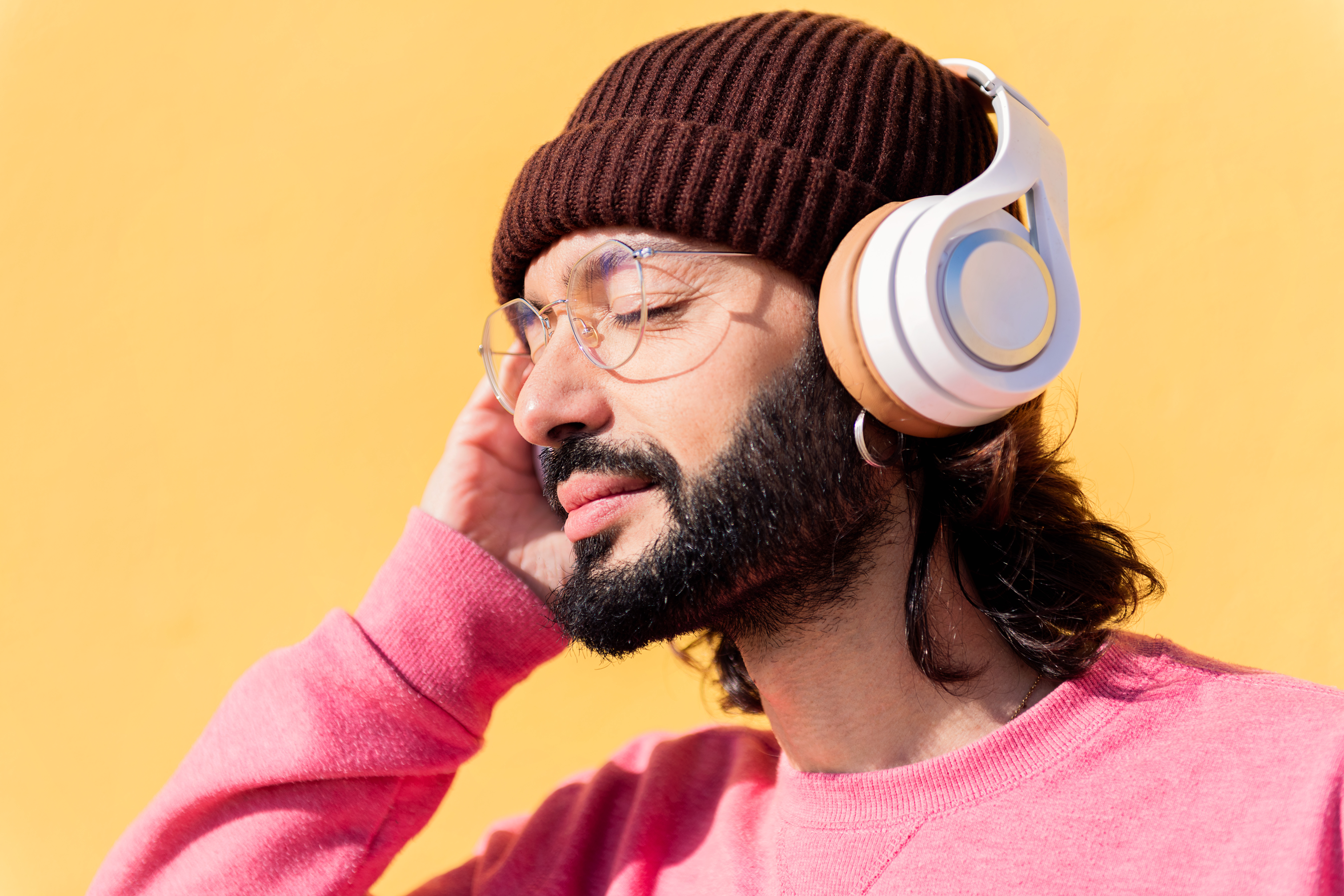young man listening to music on headphones with yellow background, concept of rhythm and positive people, copy space for text